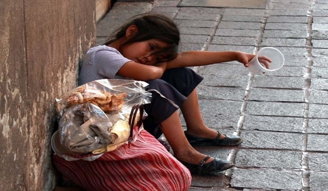 Niña en la calle pidiendo monedas